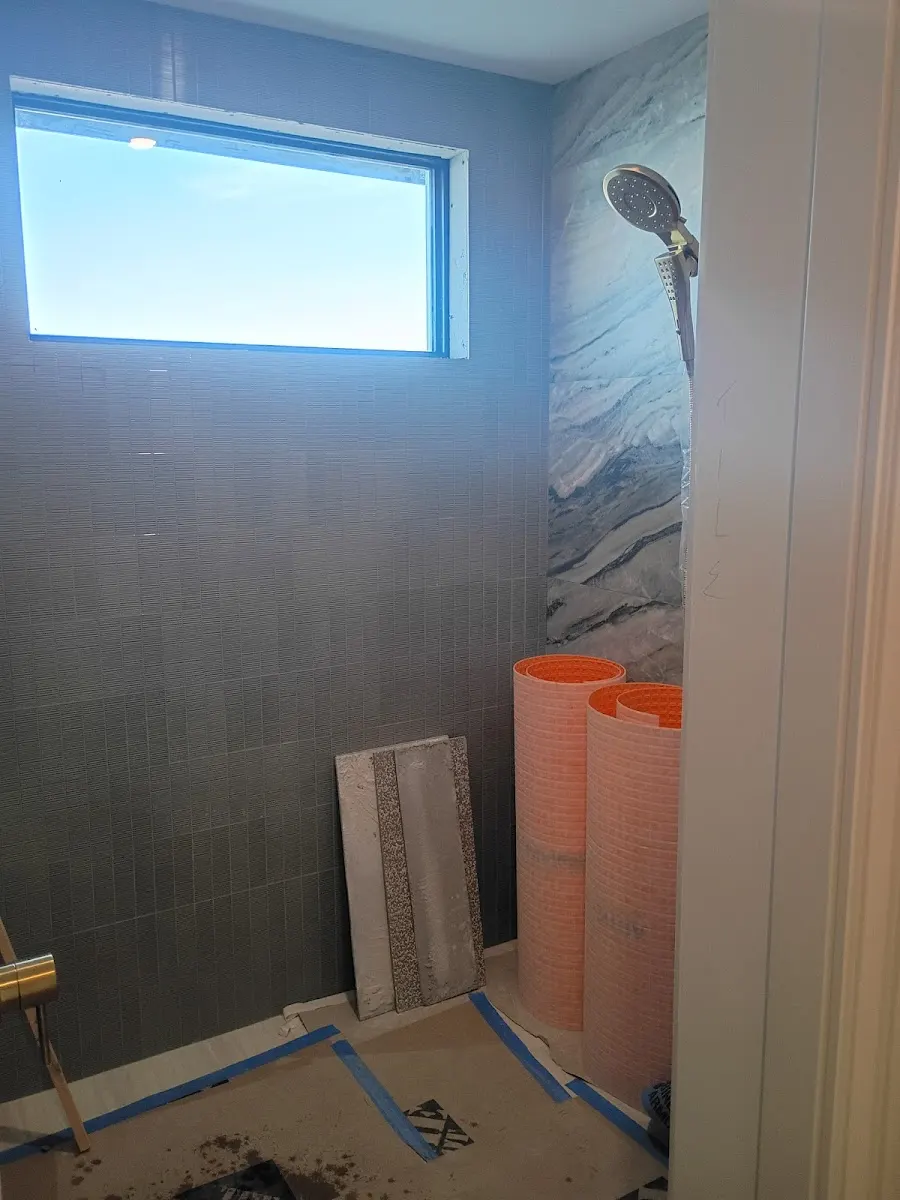 bathroom shower plumbing installation largo fl Bathroom shower plumbing remodeling project in Largo, FL featuring gray tile walls, a modern handheld showerhead, and waterproof membrane rolls.