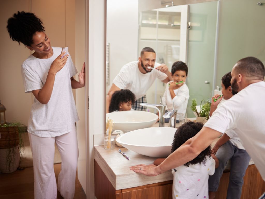 user-inserted Family brushing teeth together in bathroom, promoting healthy oral hygiene habits for children and parents in a bright, modern home setting.