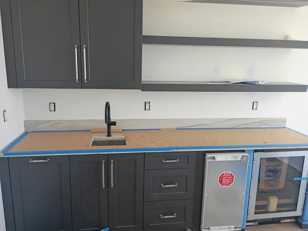 Sleek matte black single-handle kitchen faucet installed on a long wet bar countertop with dark cabinets in Largo, FL.