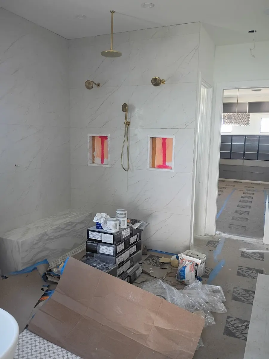 luxury shower plumbing installation largo fl Luxury bathroom remodel construction featuring gold shower fixtures, multiple shower heads, and marble wall tile installation in Largo, FL.