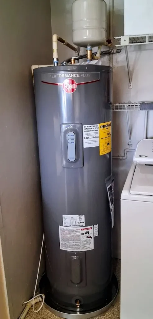 Professionally installed grey Rheem Performance Plus electric water heater tank with expansion tank in a Largo, FL laundry room.