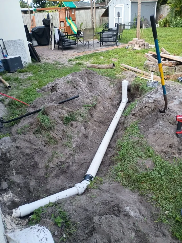 Underground residential sewer line repair and PVC pipe installation in an excavated trench in a backyard in Largo, FL.
