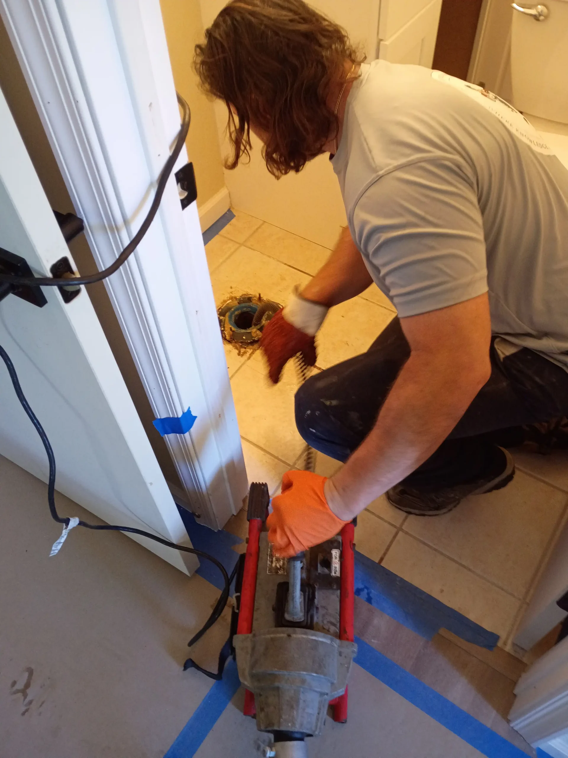 Bathroom Drain Cleaning A plumber from Positively Plumbing using a professional drain snake machine to clear a clogged main line through a toilet