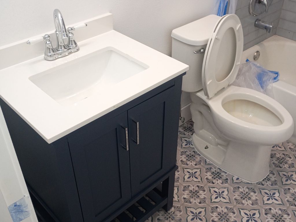 Bathroom with sink vanity and toilet after plumbing repair, showing fixtures ready for burst pipe inspection or leak prevention.