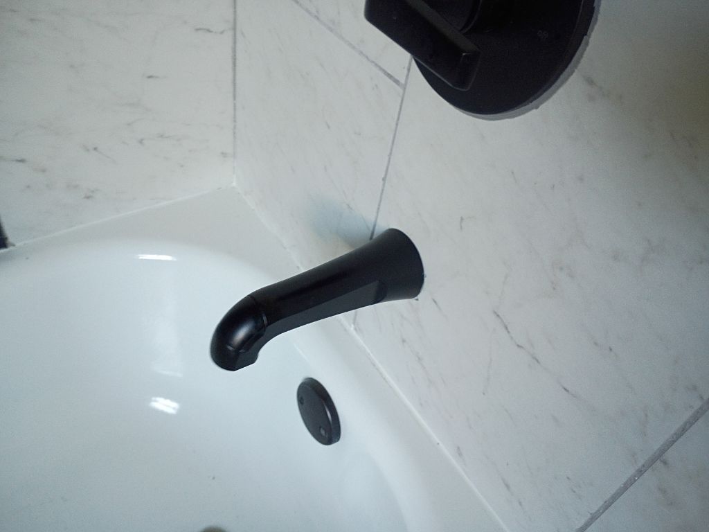 Bathtub faucet and drain in a bathroom, showing a plumbing fixture that may need drain snaking or repair service.